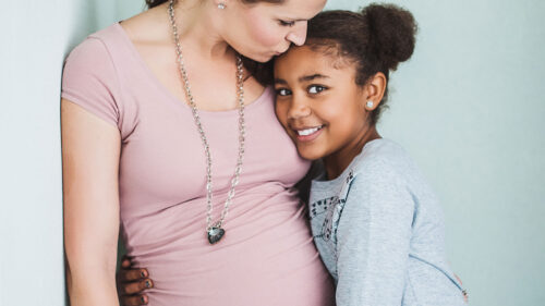 Pregnant mother hugging young daughter