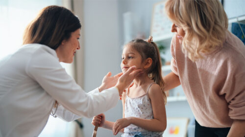 Female Caucasian doctor examining female pediatric patient with mother