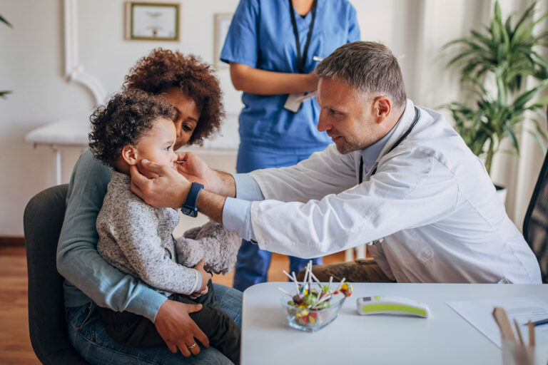 Doctor examining child sitting on mother's lap