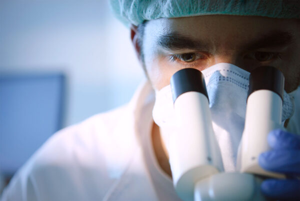 Male lab technician looking into microscope