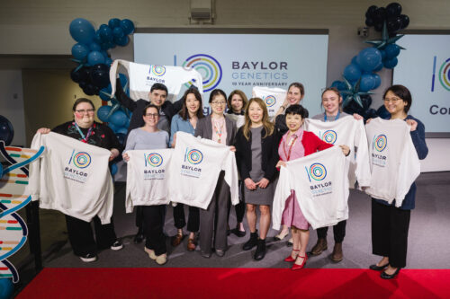 Baylor Genetics employees holding branded sweatshirt at event