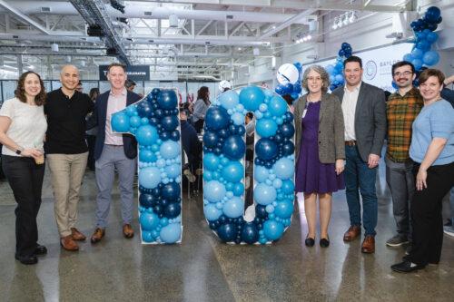 Group of Baylor Genetics employees standing around a 10 symbol made of balloons